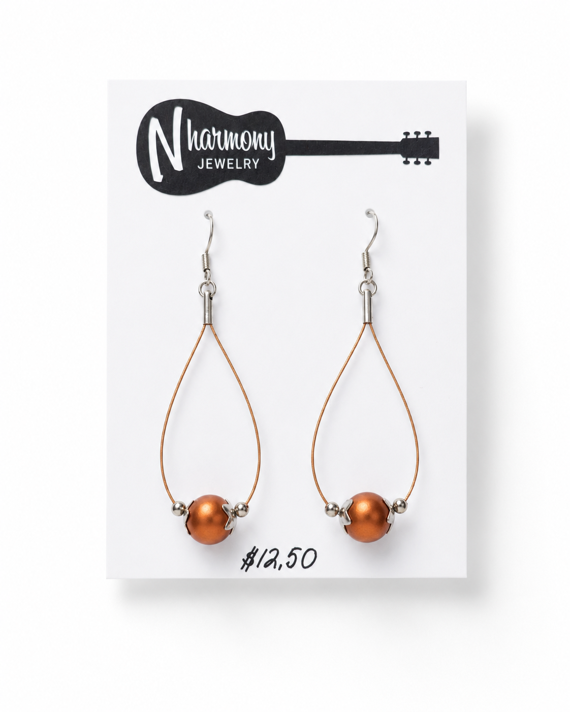 Pair of teardrop-shaped earrings with orange beads on a N'Harmony Jewelry card.