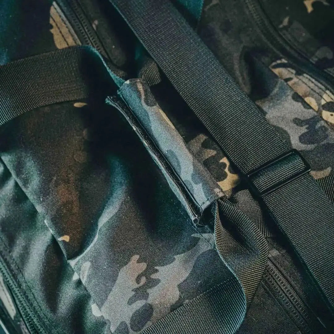Camouflage duffle bag with black straps and zipper detail