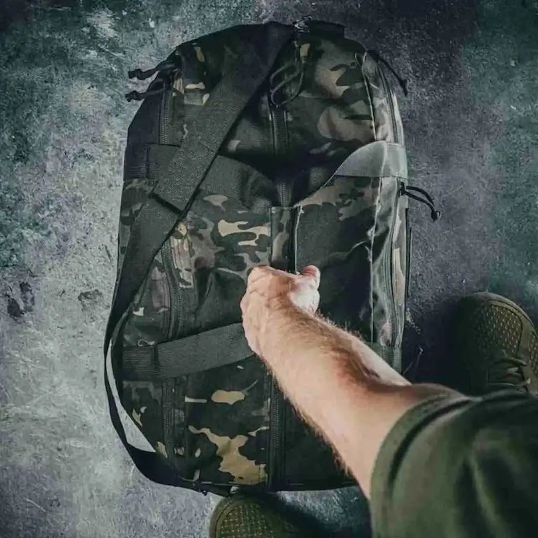 Camouflage duffle bag with a hand reaching for the zipper.