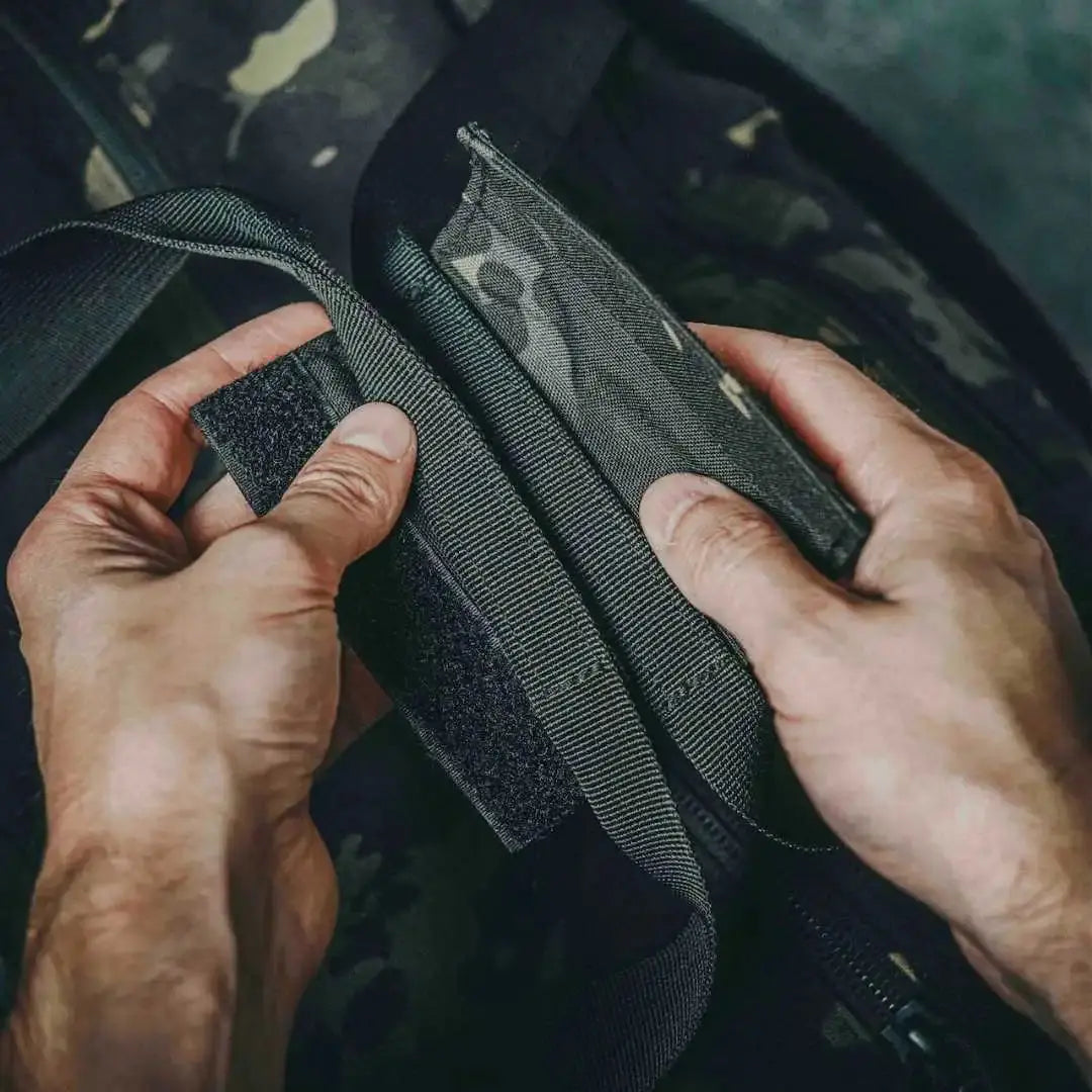 Hands adjusting the velcro closure on a camouflage 72-hour duffle bag.