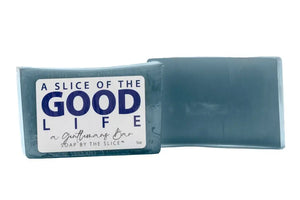 Two bars of dark soap, one with a label that reads "A SLICE OF THE GOOD LIFE", "a Gentlemans Bar", "SOAP BY THE SLICE", and "5oz".