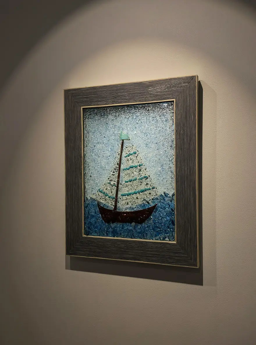 Framed glass sailboat art: A sailboat with a brown hull and turquoise accents sailing on blue glass against a light blue background.
