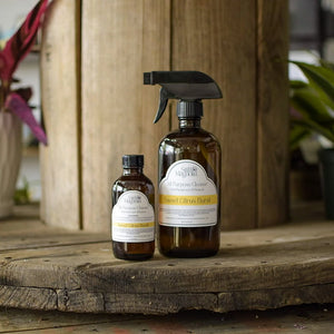 Two amber glass spray bottles of Still Magnolia All Purpose Cleaner with Sweet Citrus Burst labels.