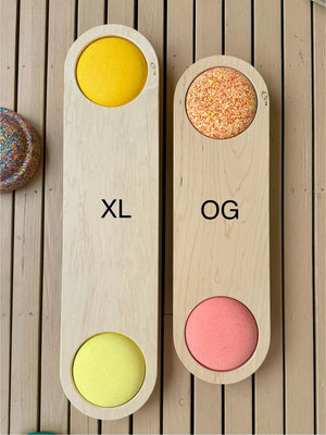 Two wooden balance boards, one labeled XL with yellow circles and the other labeled OG with a speckled circle.