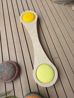 Maple balance board with yellow cushions on a wooden deck