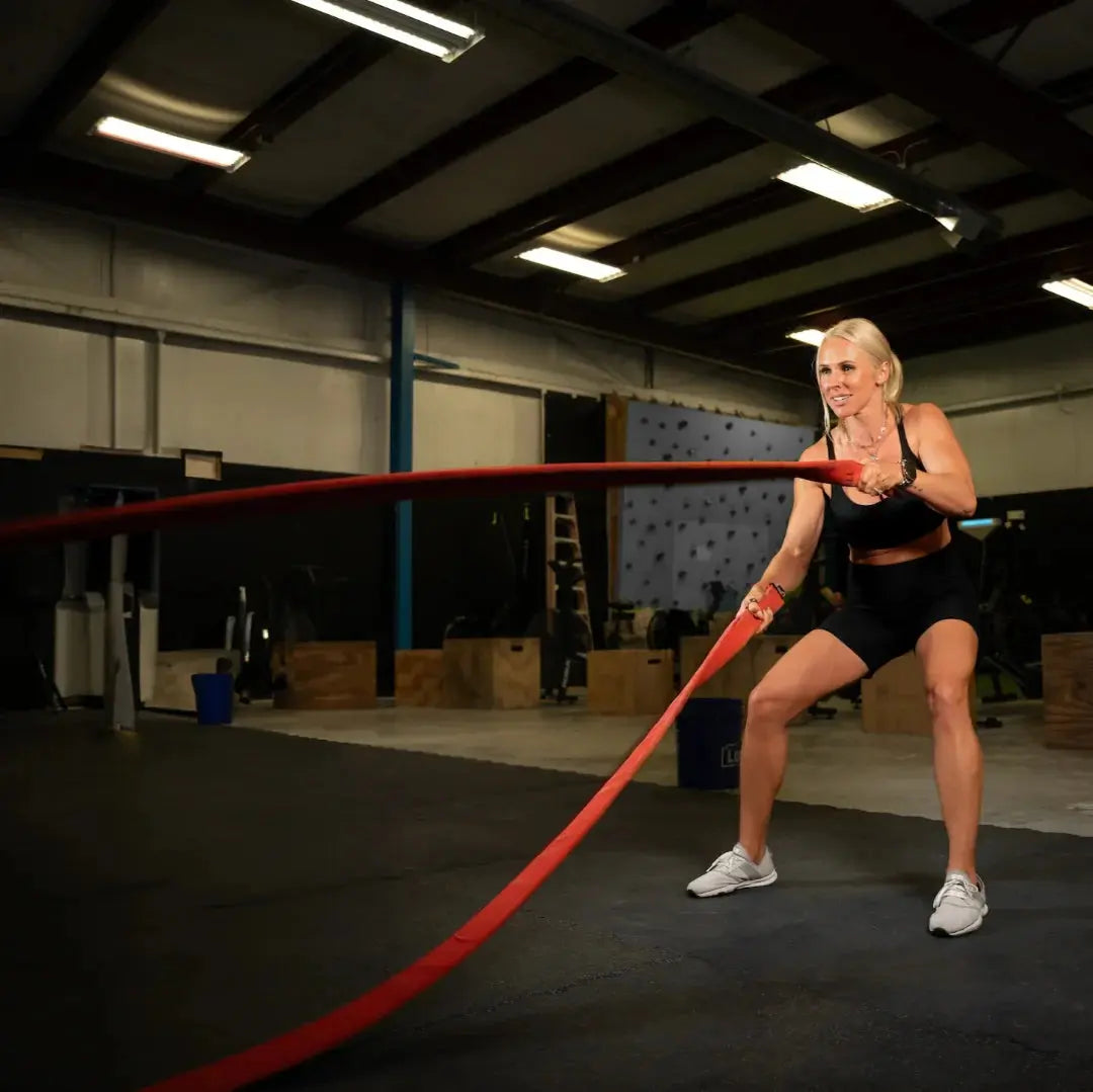 Woman using a red 30-foot battle rope for exercise.