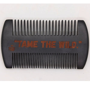 Wooden beard comb with \"Tame The Wild\" engraved on it, showing comb's teeth and overall shape. A grooming tool for beard care.