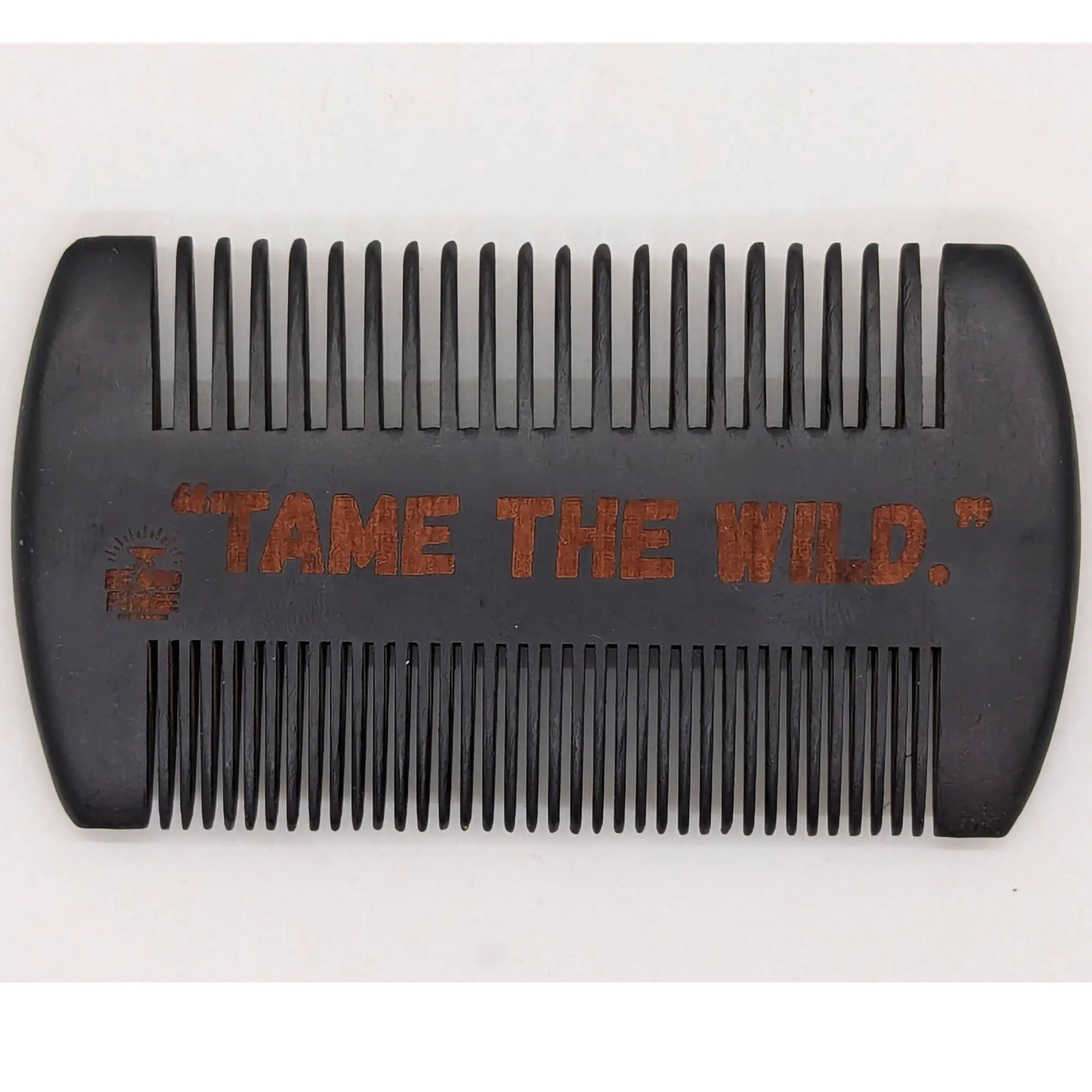 Black wooden comb with "TAME THE WILD." engraved on it.