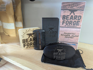 Beard grooming set with wooden comb, brush, beard oil, and box from Beard Forge by ResilScents on a wood shelf.