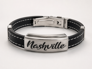 Black leather bracelet with silver tag displaying 'Nashville' on a white background