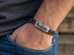 Person wearing a bracelet with 'Nashville' engraved on it, against a blurred background.