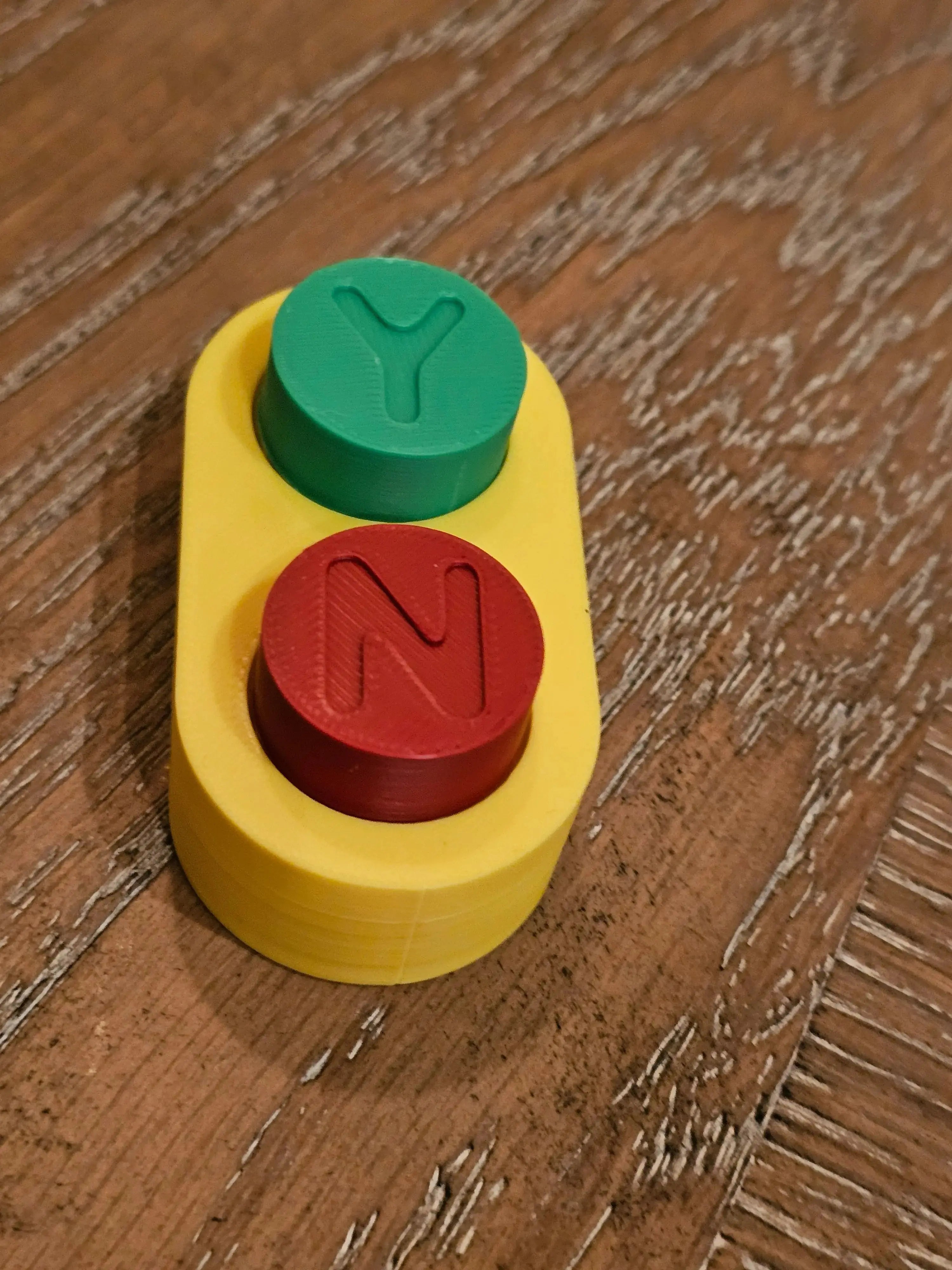 Yellow fidget toy with red "N" button and green "Y" button.