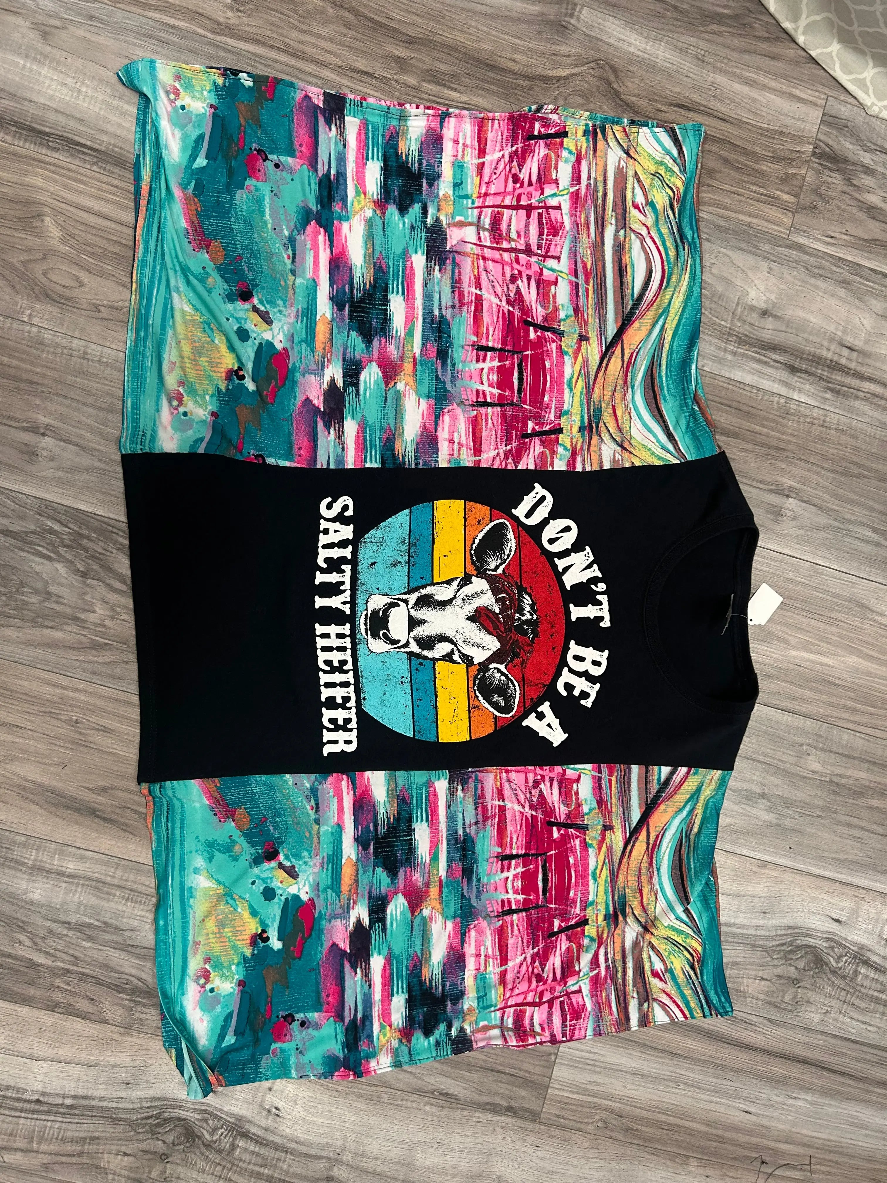 BOHO PONCHO SLEEVE TEE featuring a cow graphic with "DON'T BE A SALTY HEIFER" text, showcased on a wood surface.