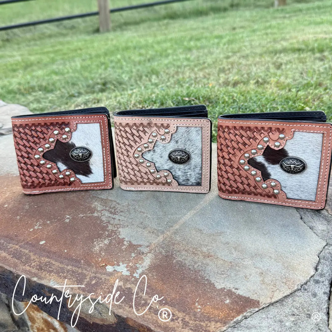 Three men's cowhide wallets with tooled leather and conchos.
