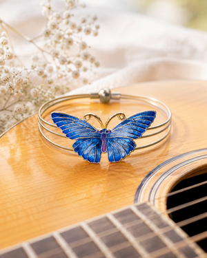 Blue butterfly bracelet on a guitar with flowers in the background