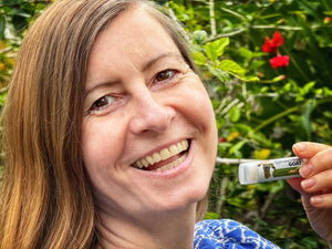 Woman smiling and holding Appalachian Goat Coconut Milk Lip Butter tube.