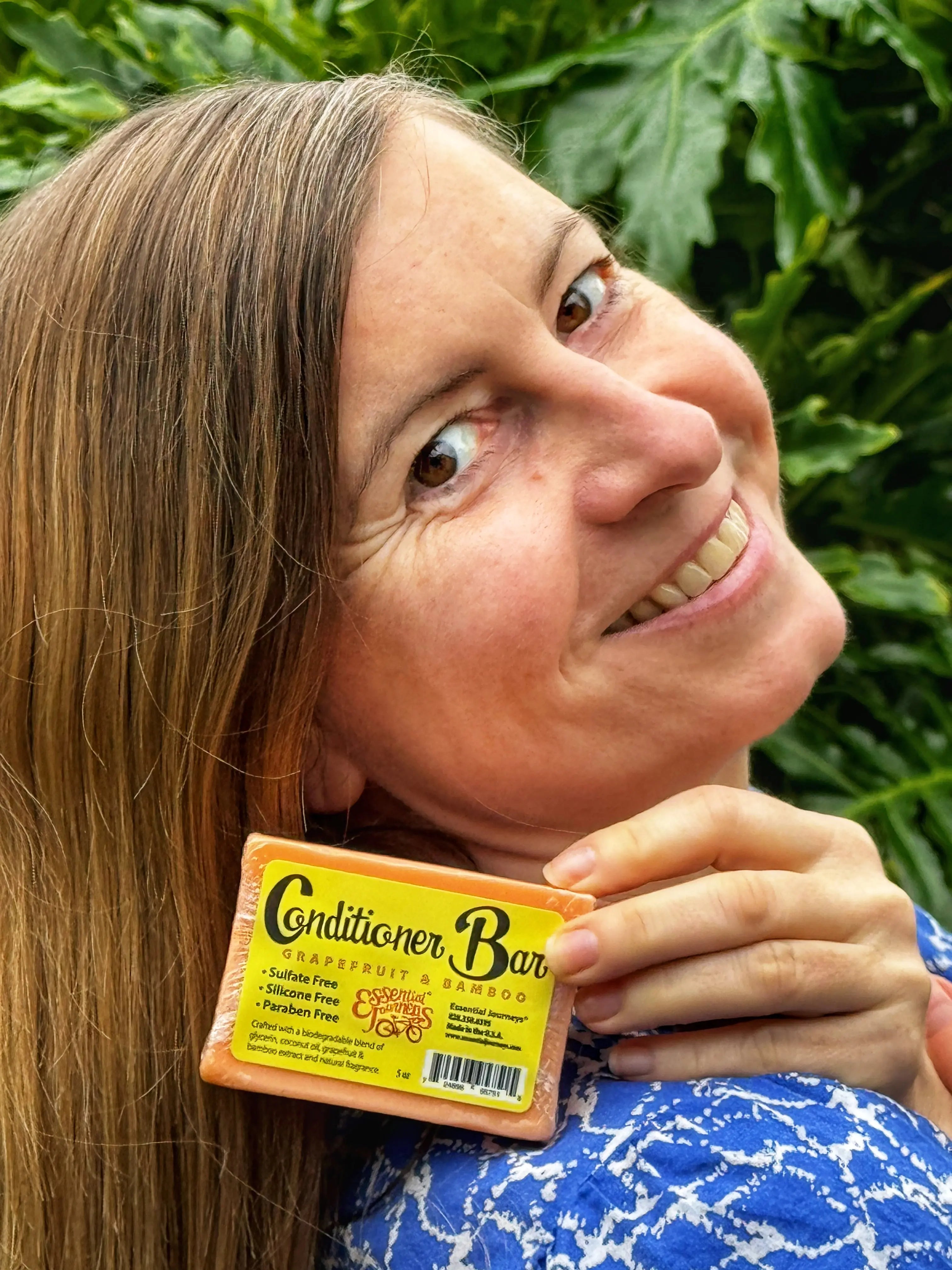 Orange conditioner bar with "Grapefruit & Bamboo" label held by a woman.