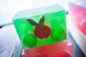 Green glycerin soap slice with embedded apple and leaves.