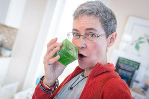 Woman drinking from a green cube-shaped soap in a glass.