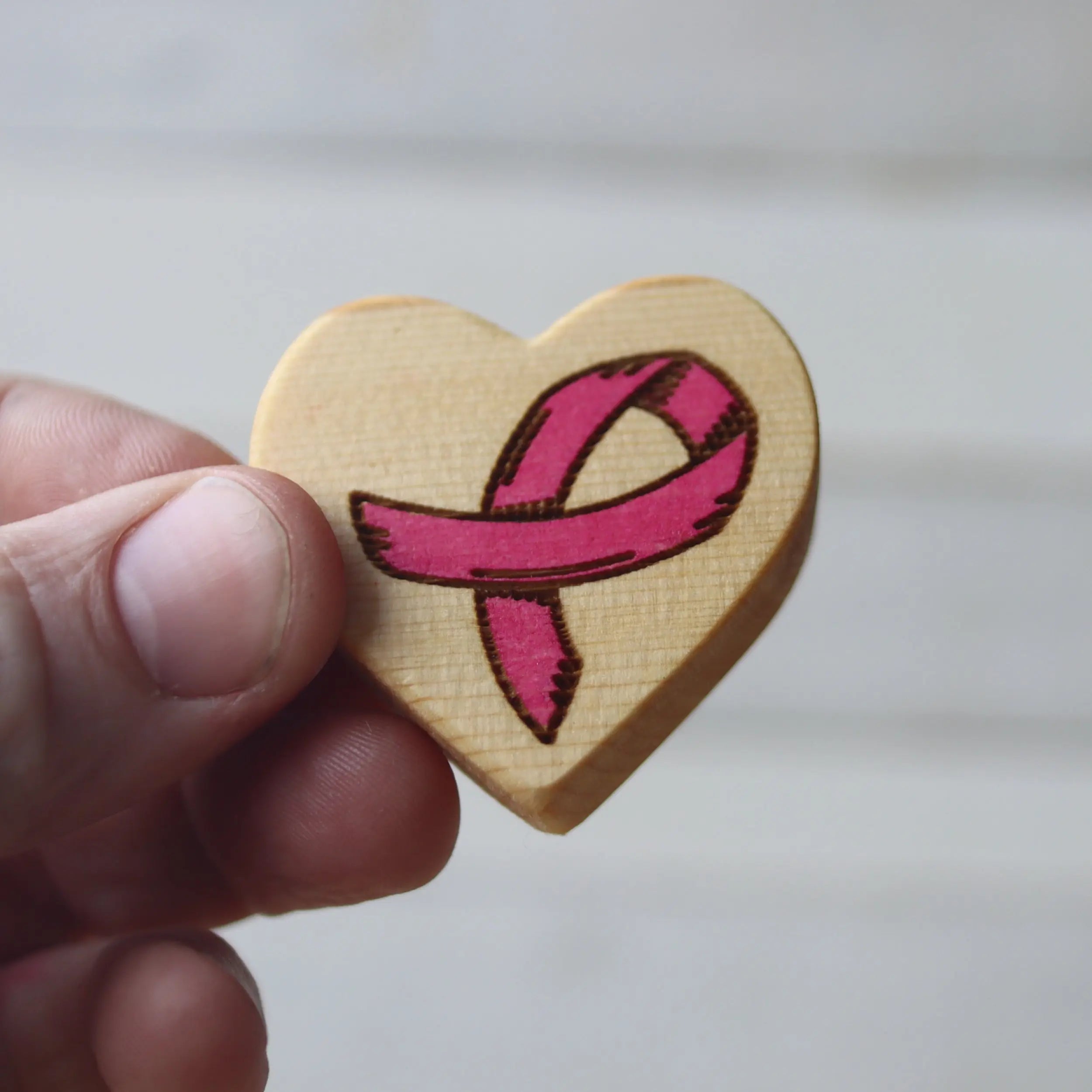 Wooden heart with pink breast cancer awareness ribbon