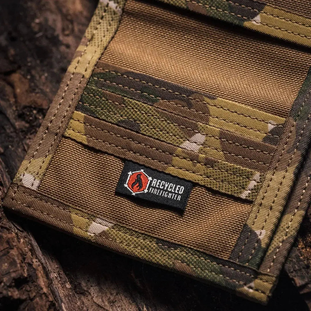 Close-up of a camouflage wallet with a "Recycled Firefighter" label made of combat leather.