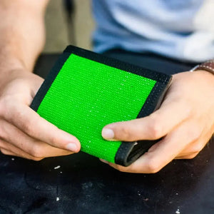 Green wallet with black trim held in two hands
