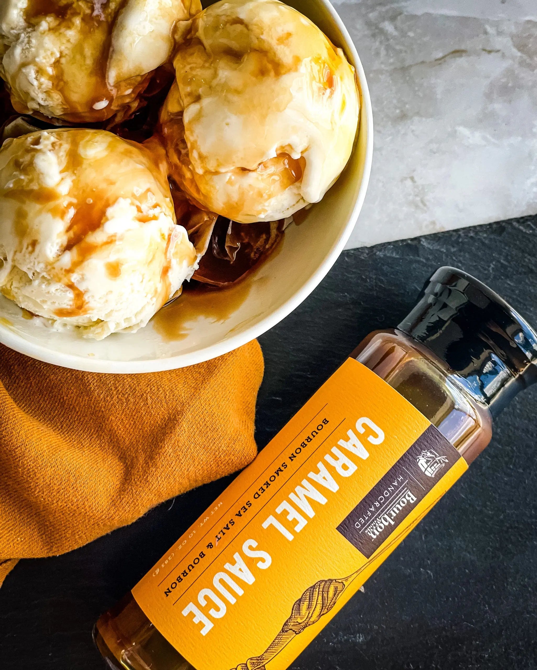 Bourbon caramel sauce bottle next to a bowl of ice cream