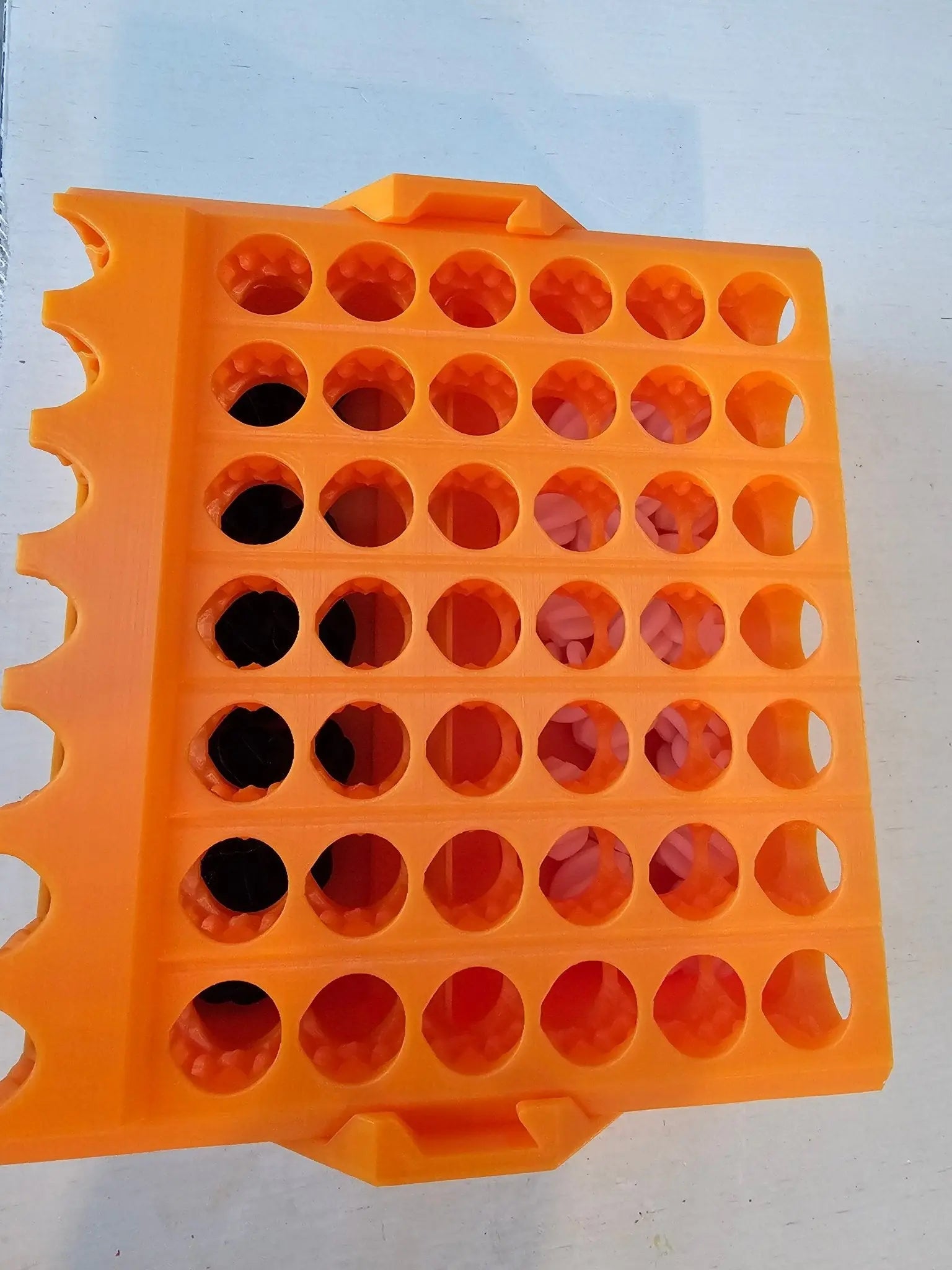 Orange 3D Printed Connect 4 Game with Self-Sorting Feature and Black and Pink Discs.