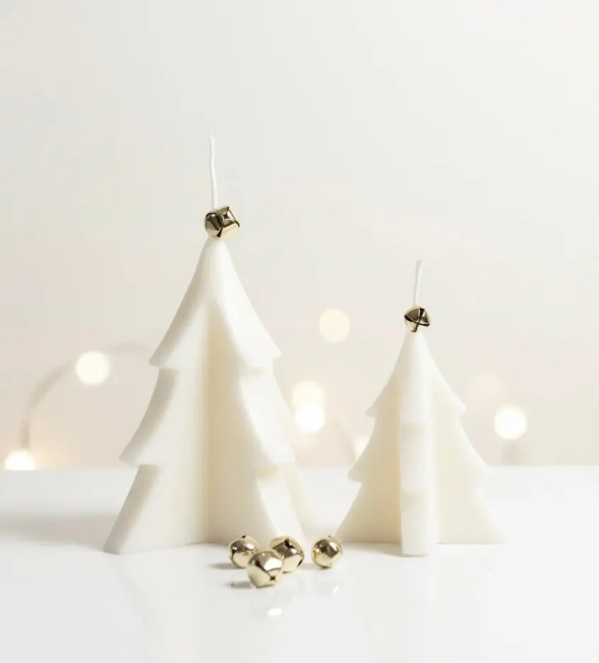 Two white Christmas tree candles with gold jingle bells on top and scattered around.