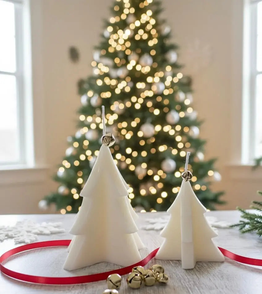 Cream colored Christmas tree shaped candles with gold bells on a wooden table