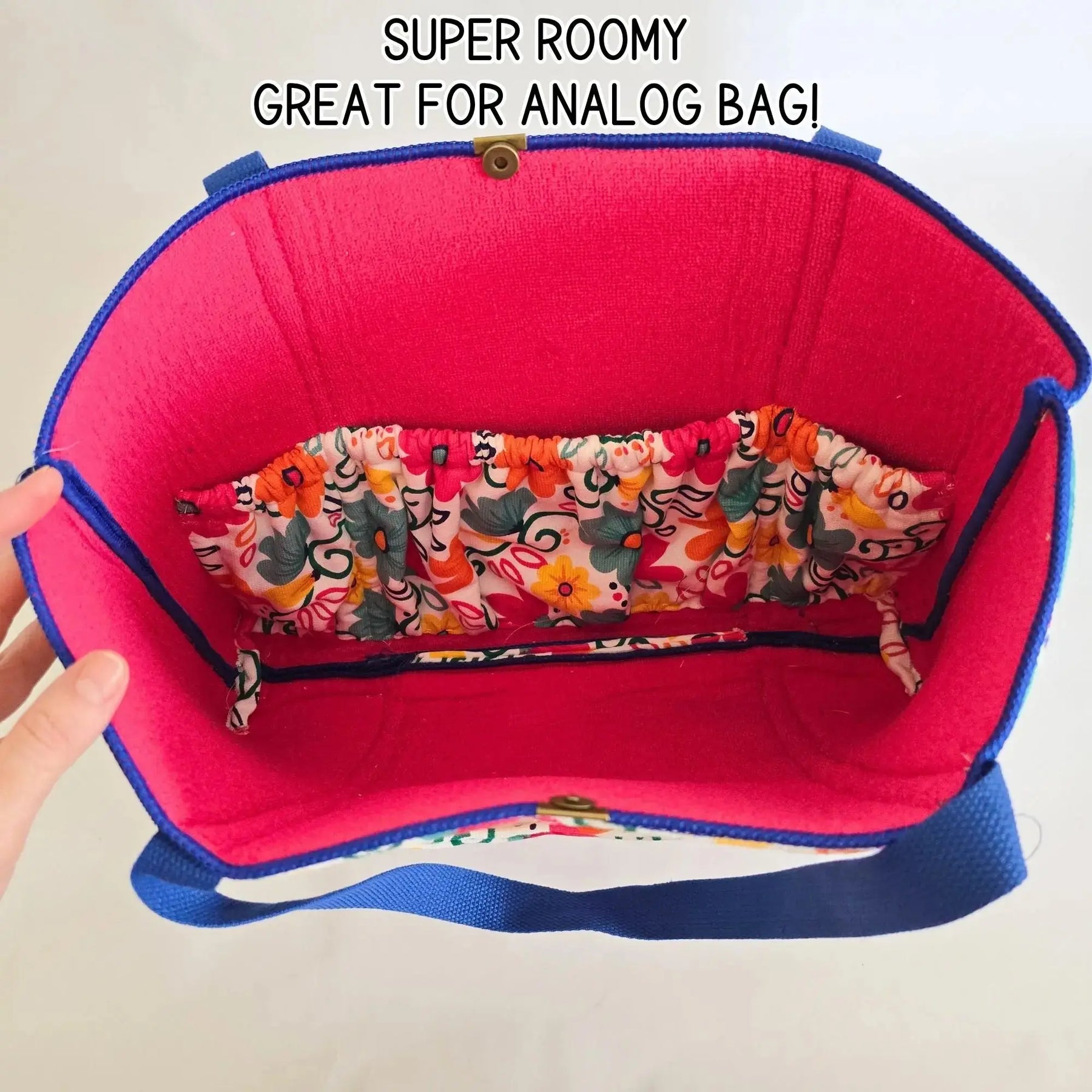 Interior of a pink tote bag with blue trim and colorful floral print elastic pockets.