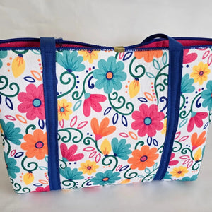 Colorful floral tote bag with blue straps on a white background.