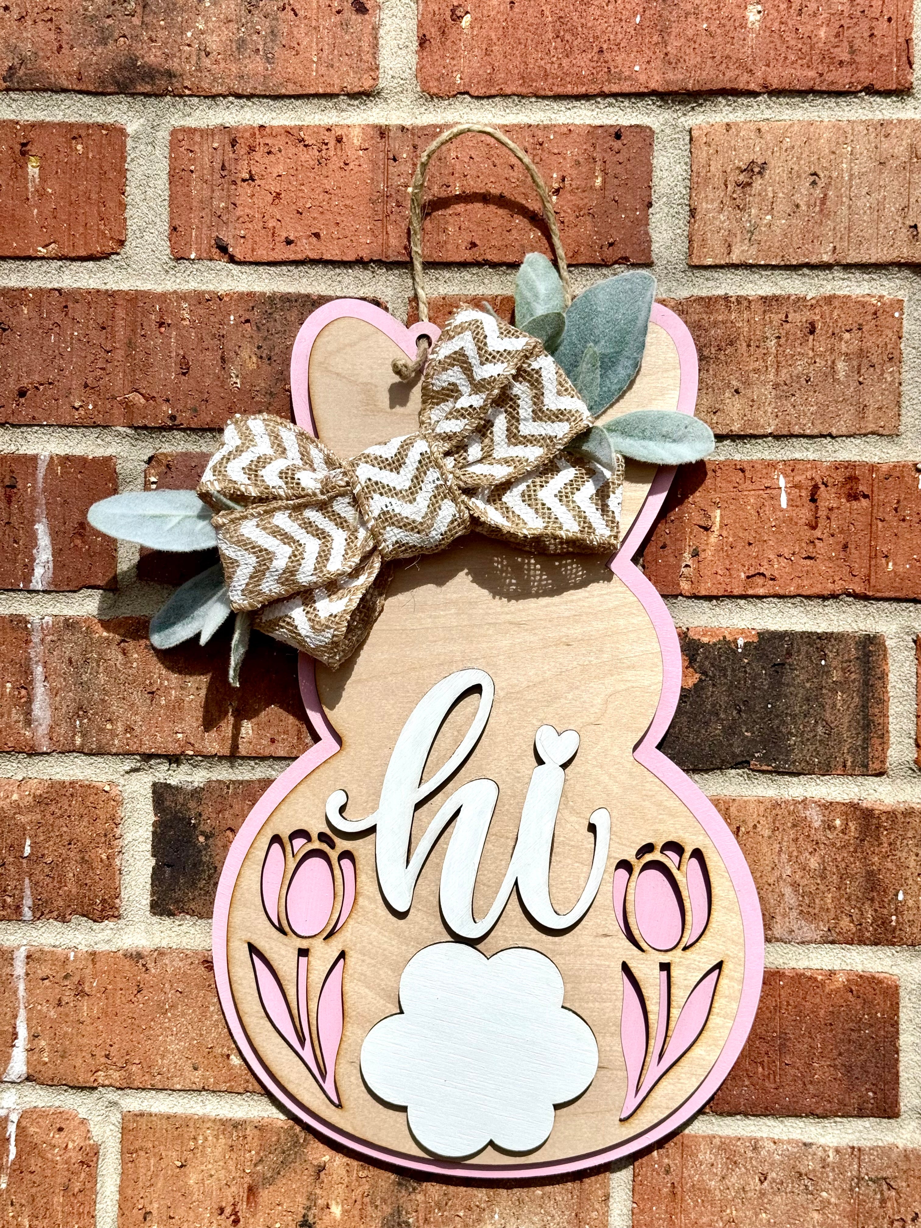 Wooden bunny door hanger with burlap bow, tulips, and pink trim for Easter decor.