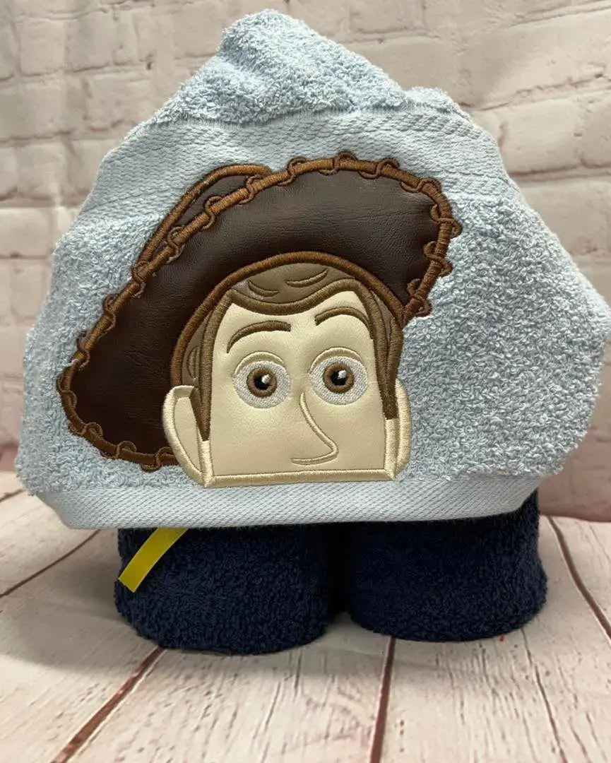 Cowboy hooded towel: a light blue towel featuring an embroidered Woody from Toy Story design with a brown cowboy hat.