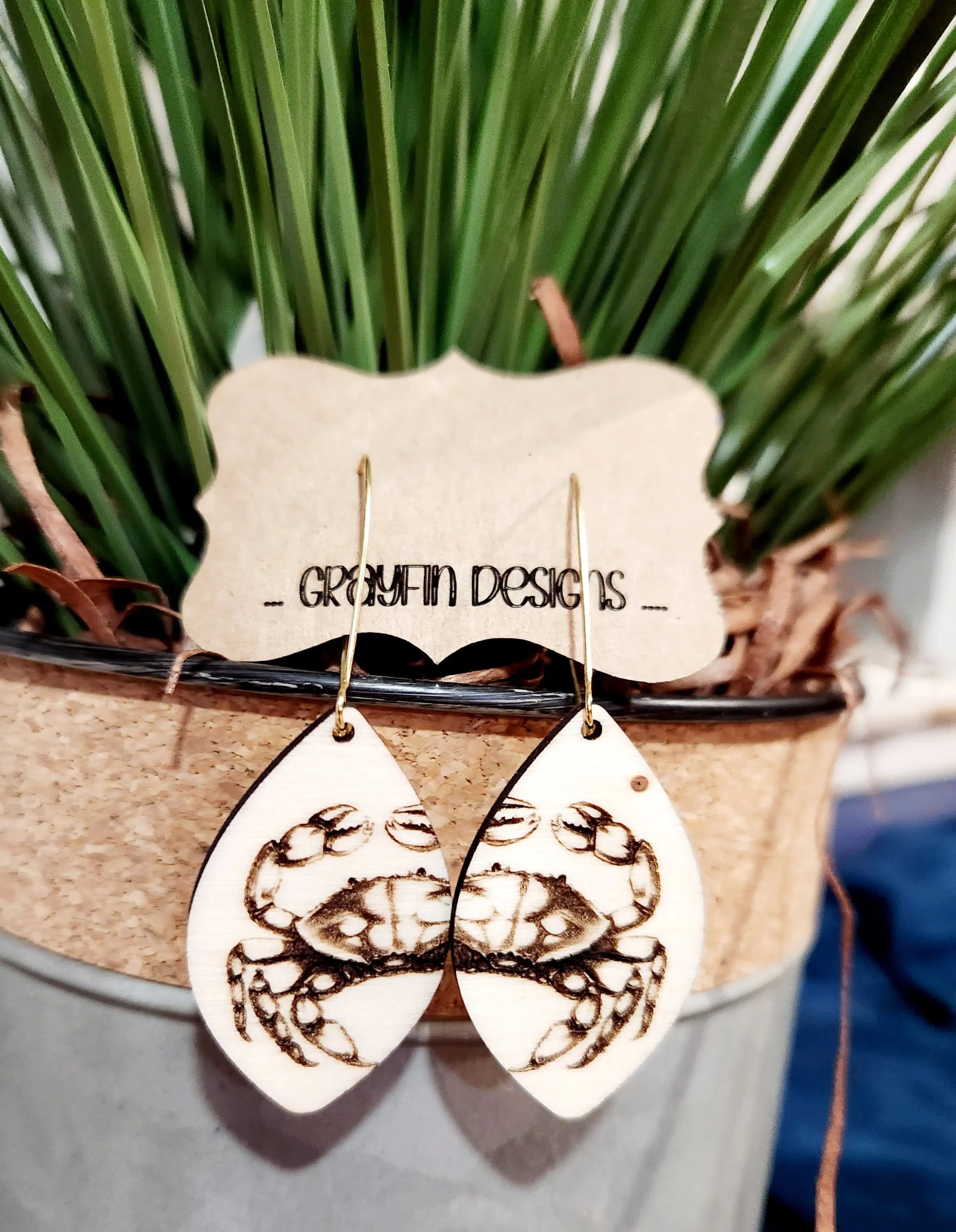 Crab dangle earrings made of wood with gold-colored hooks. Grayfin Designs present.