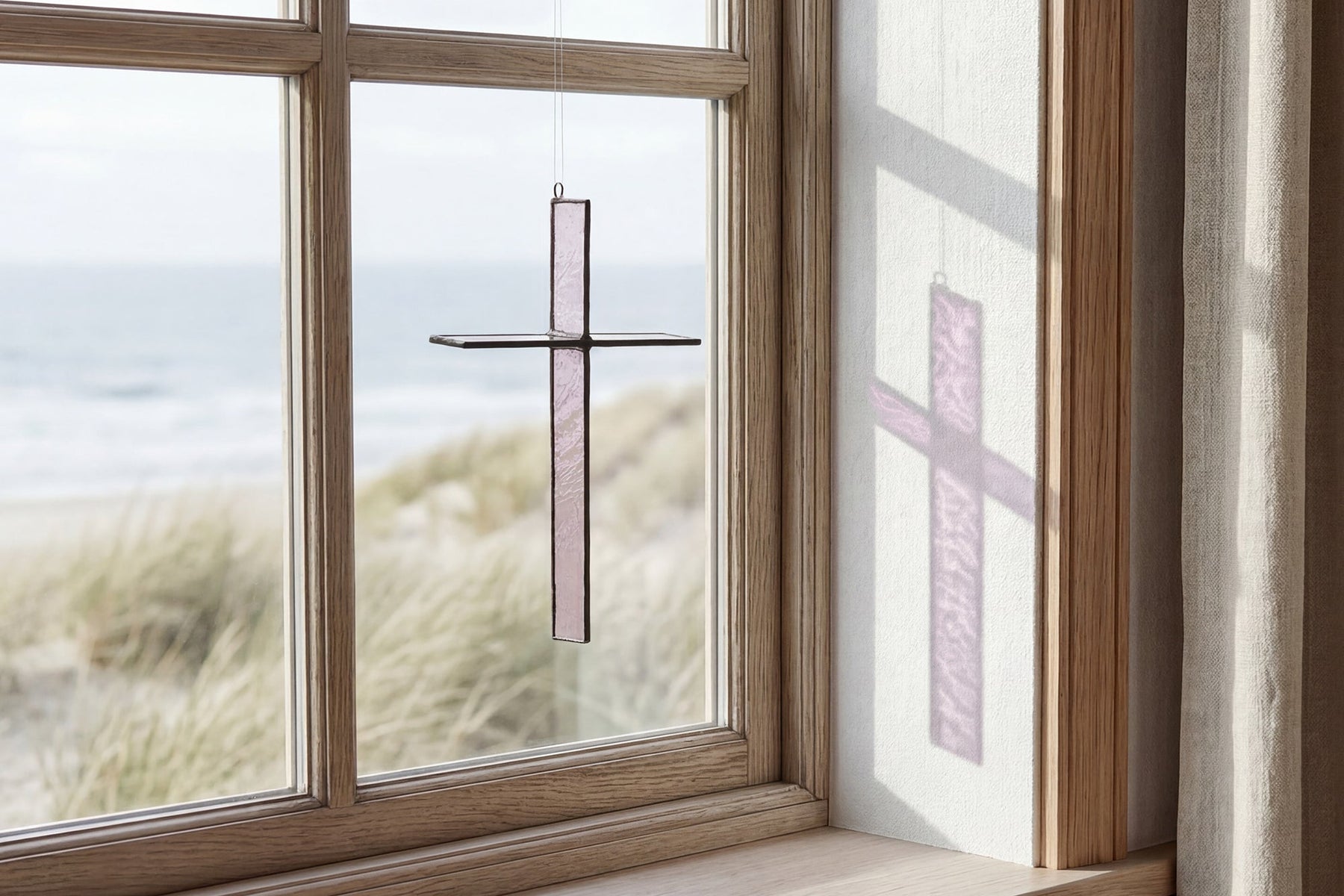 Burnt Amber Cross Suncatcher hanging in a window and catching natural light