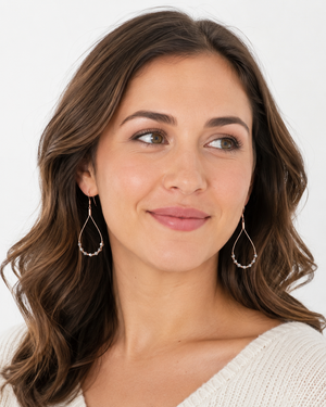 Woman wearing gold hoop earrings on a white background