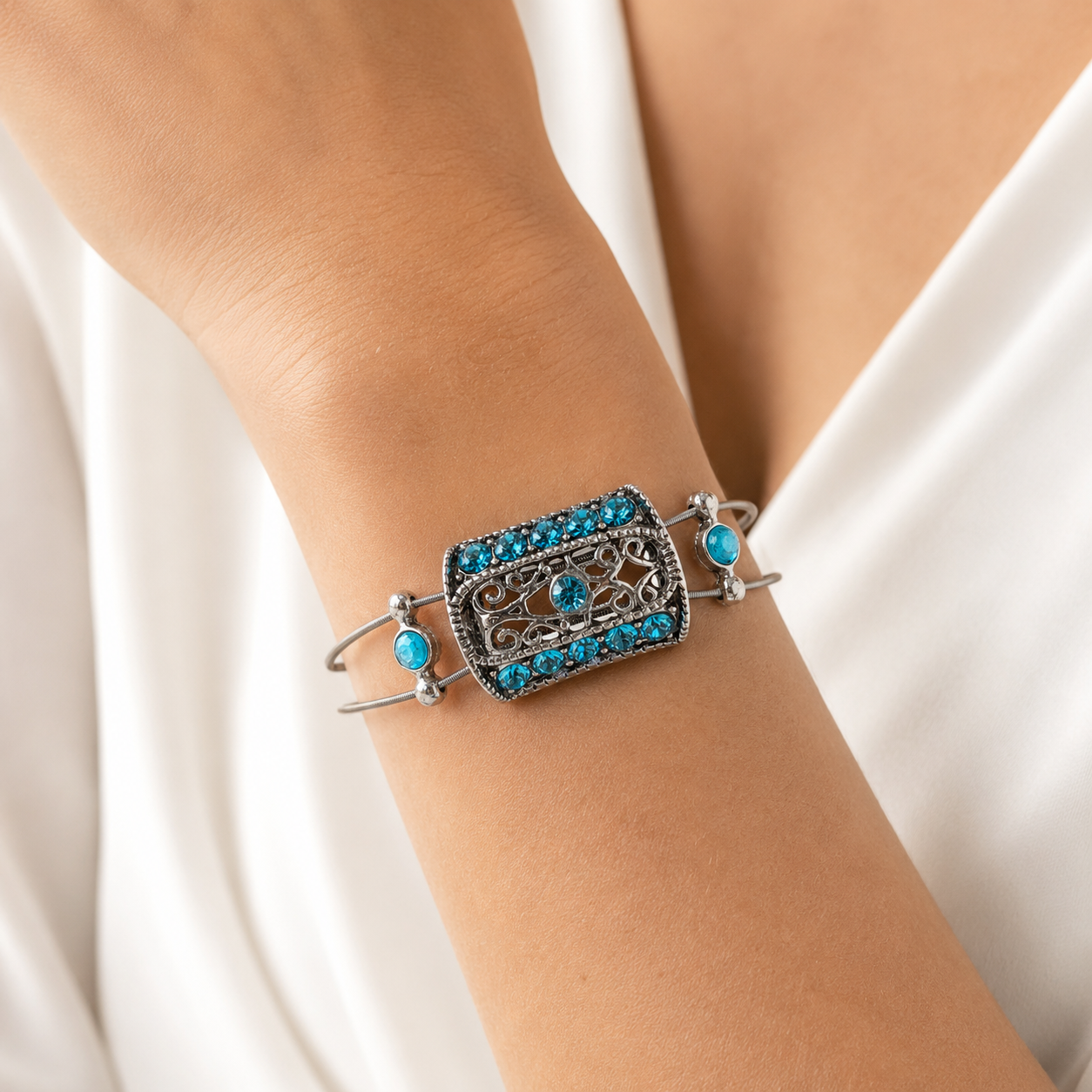 Silver bracelet with blue gemstones on a wrist against a white background