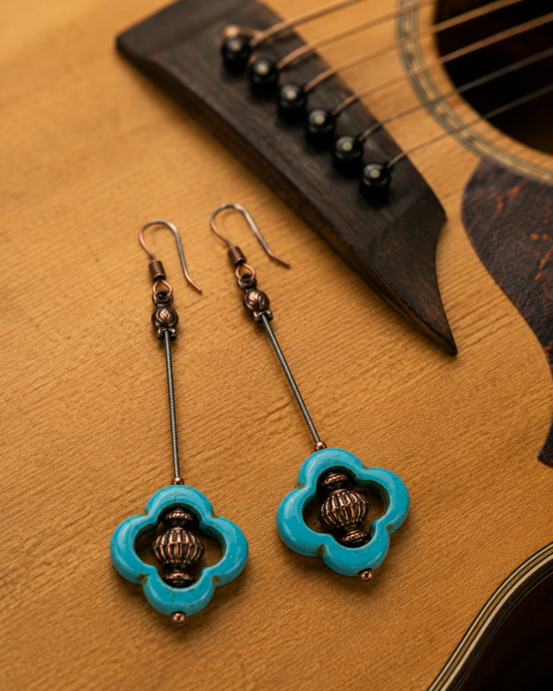 Blue floral earrings on an acoustic guitar
