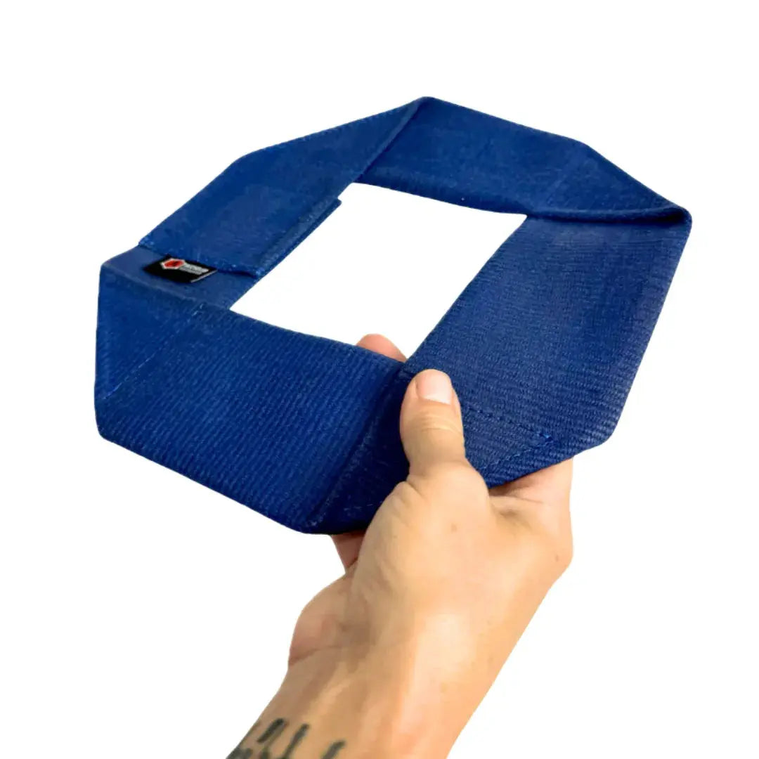 Blue fire hose dog frisbee held by a hand against a white background.