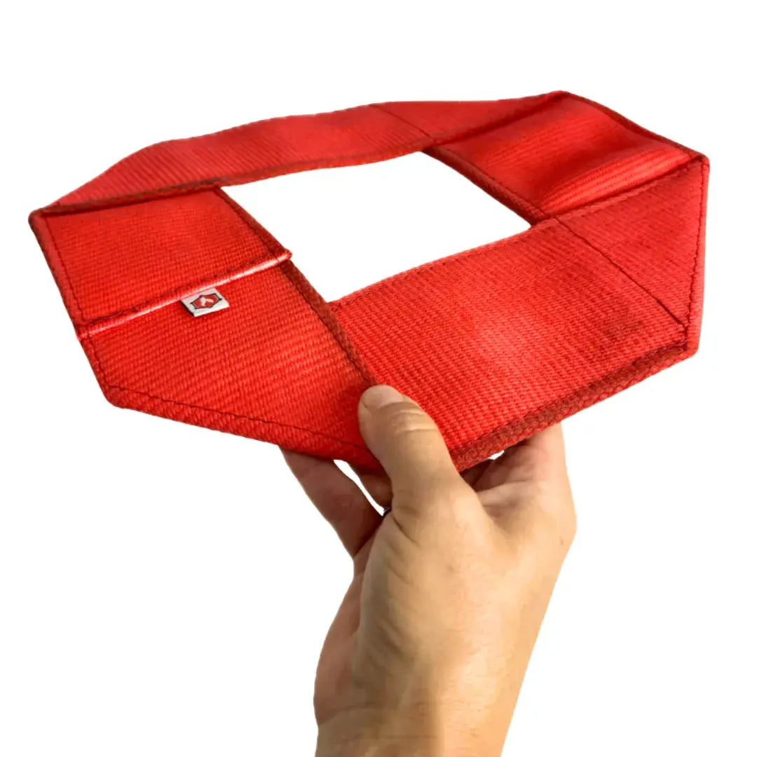 Red fire hose dog frisbee held in a hand.