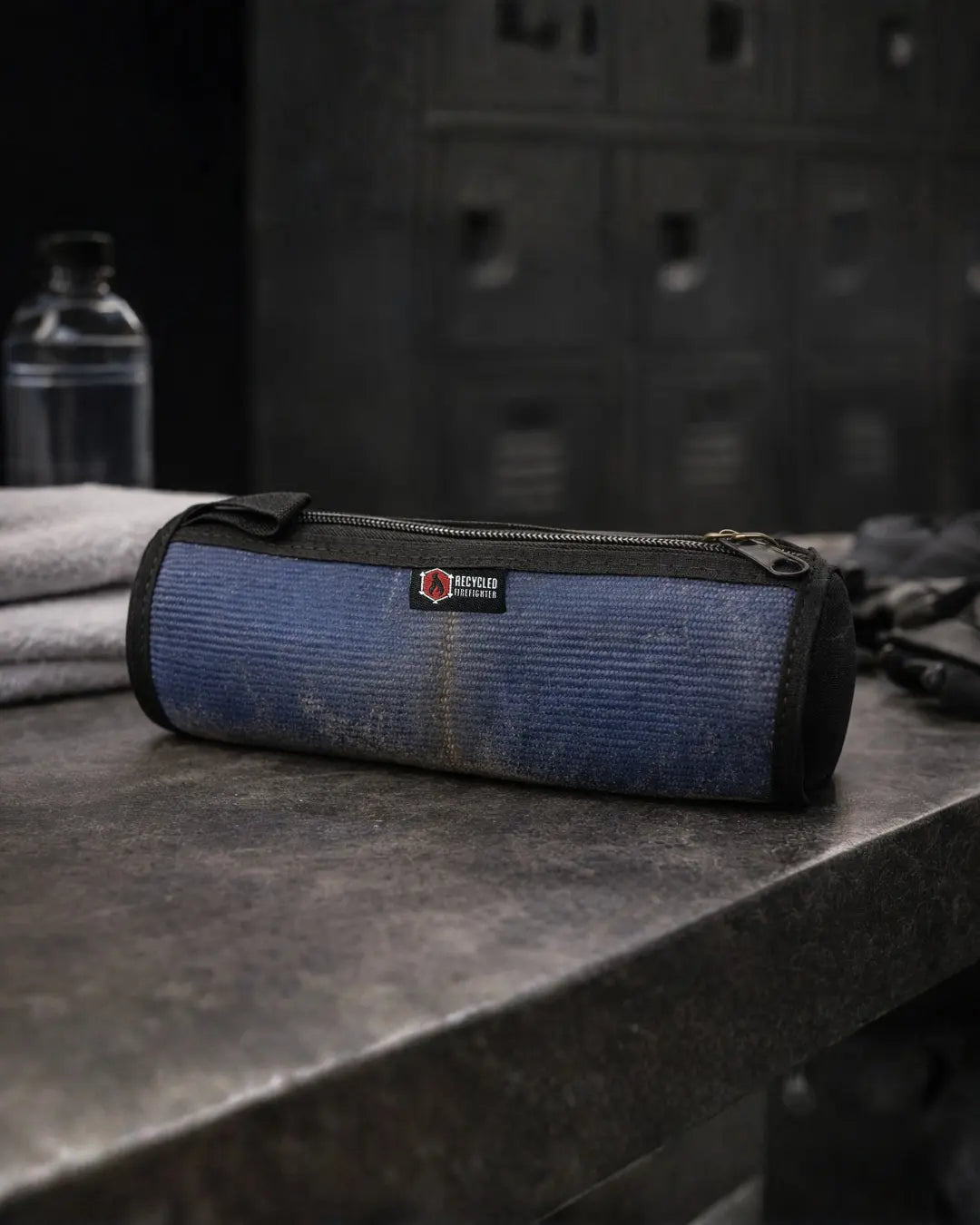 Blue and grey corduroy toiletry bag with a red and white "Recycled Firefighter" logo.
