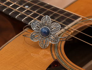 Decorative flower-shaped guitar pick on an acoustic guitar