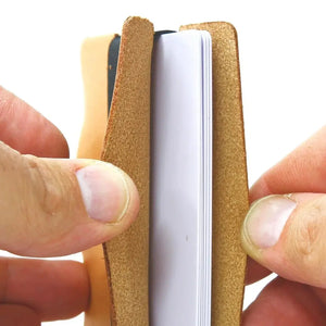 Hands holding a full grain leather card wallet with a white notebook inside.