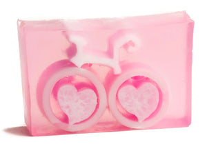Pink clear soap slice with a white bicycle design with heart-shaped wheels.