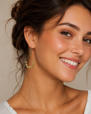 Close-up of a woman wearing gold hoop earrings with a neutral background