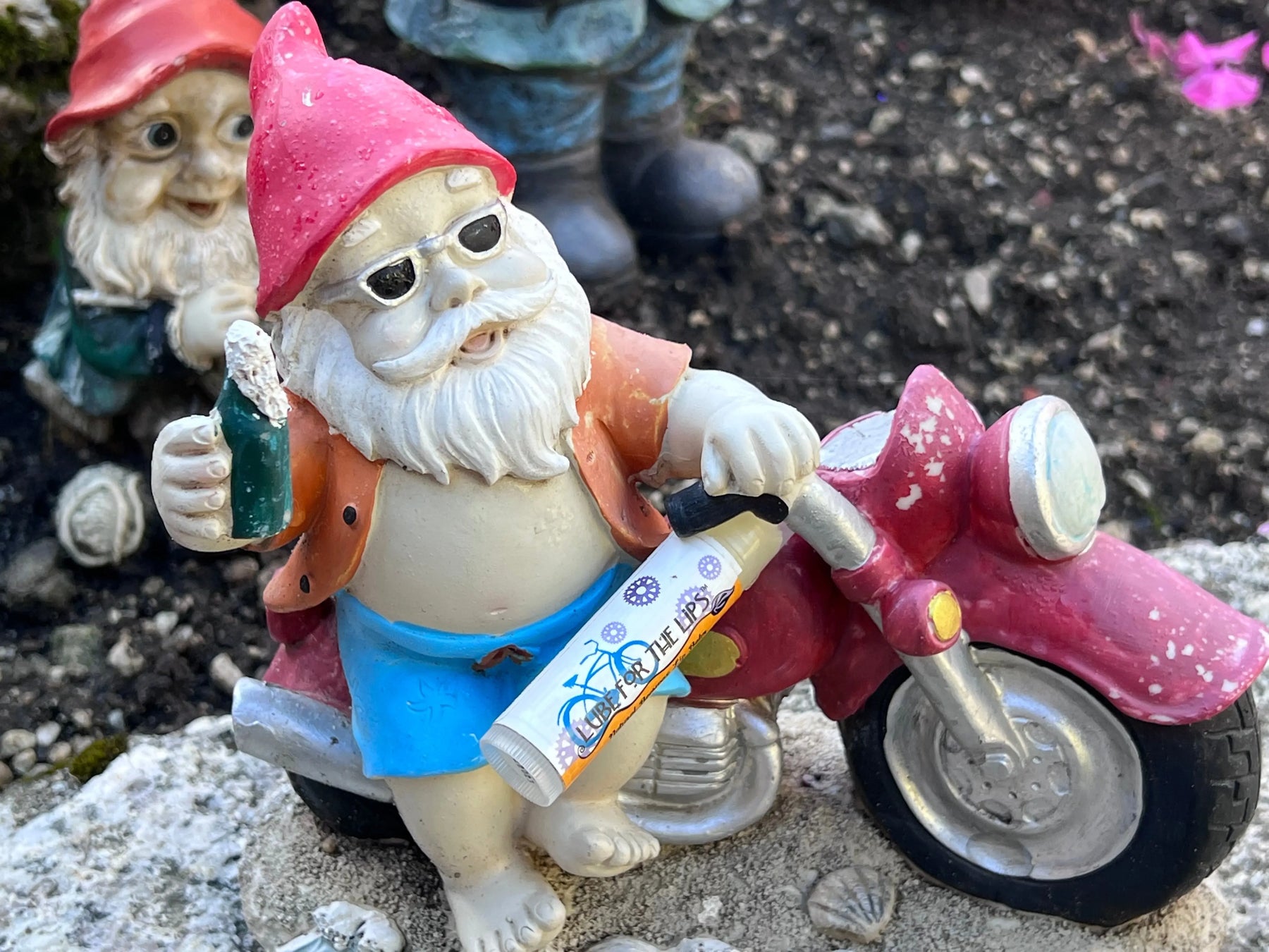 Essential Journeys Honey Vanilla SPF 15 lip balm tube held by gnome figurine.