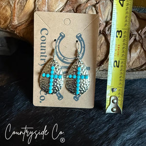 Silver cross dangle earrings with turquoise stones on hammered finish.