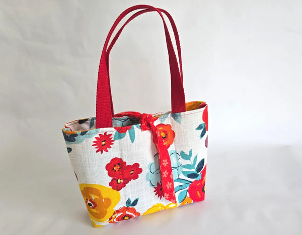 Floral tote bag with red straps, ideal for carrying a Bible and church essentials.