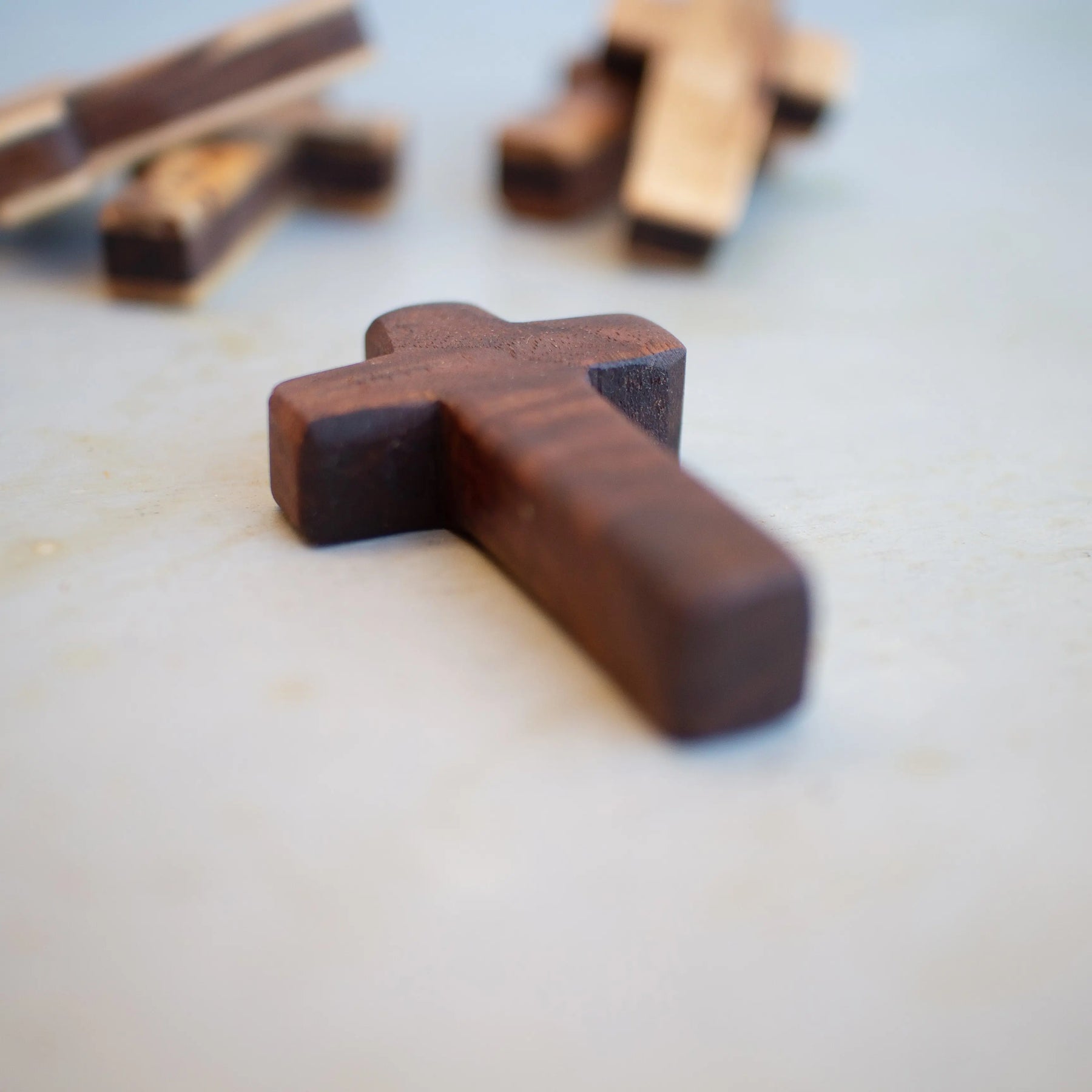 Several wooden pocket crosses scattered on a light surface.